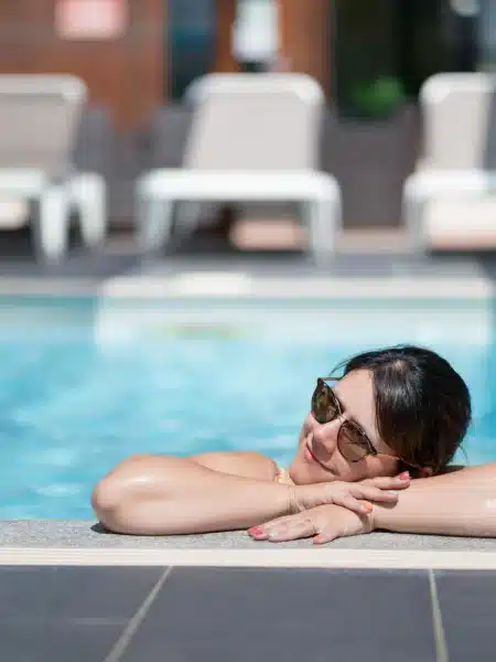 Femme se relaxant au bord de la piscine chauffée, camping avec piscine en Alsace